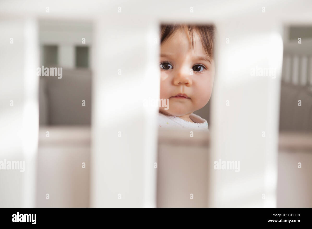 Baby girl sitting up in crib Stock Photo