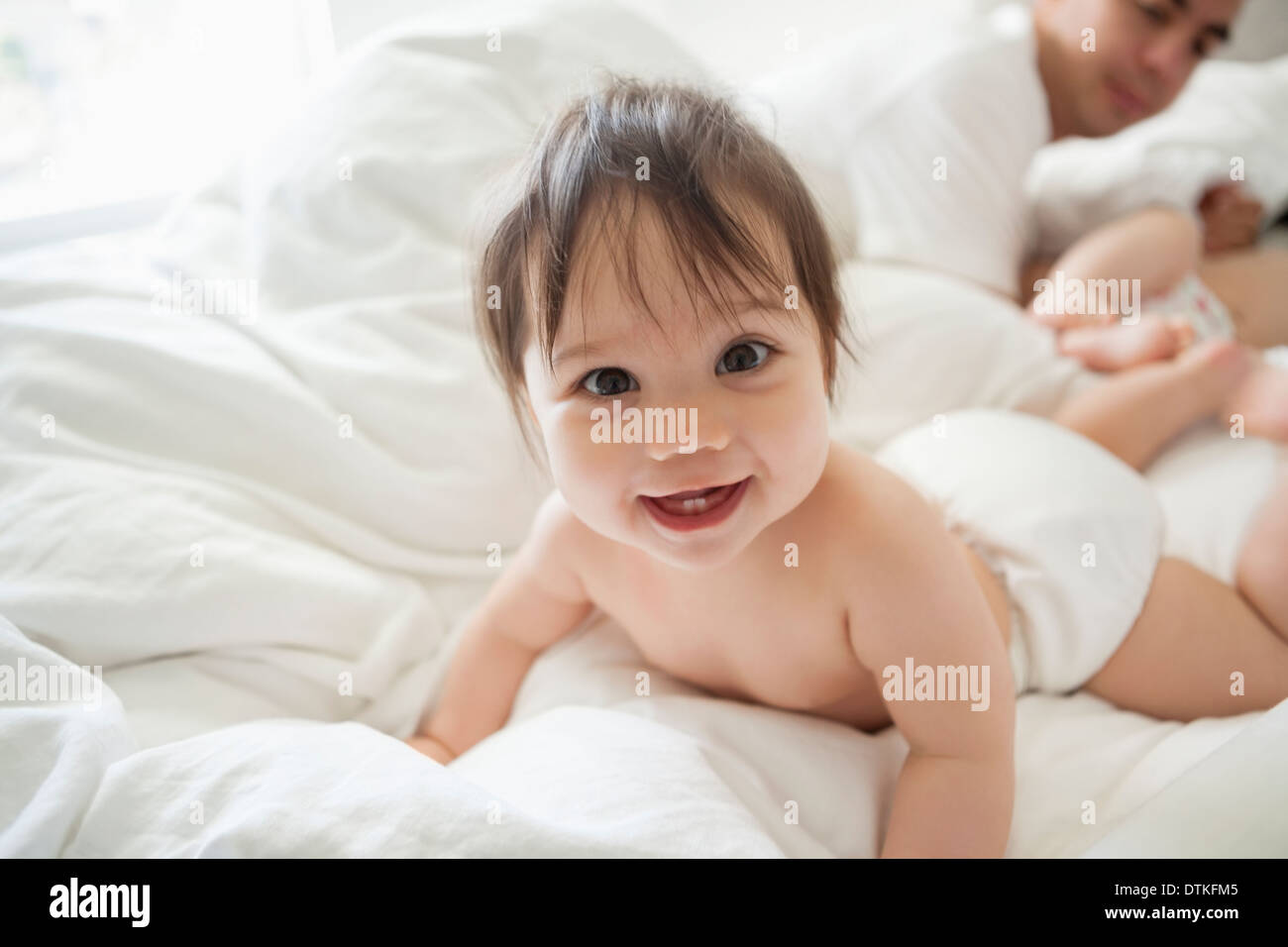 Baby girl crawling in bedsheets Stock Photo