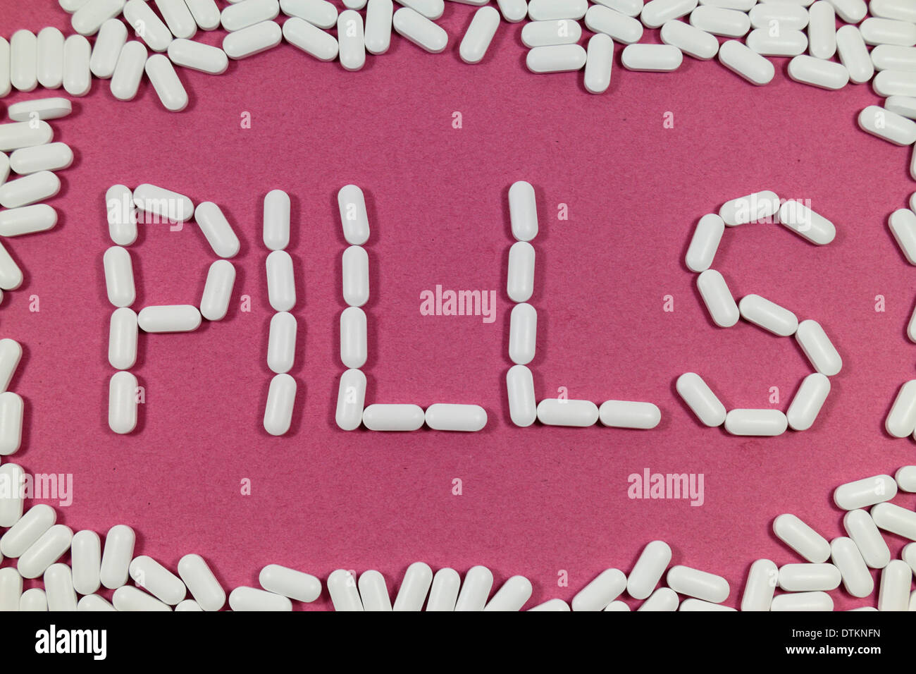 White pills on a red/pinks background spelling 'PILLS'. Stock Photo