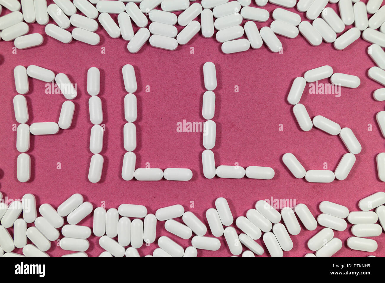 White pills on a red/pinks background spelling 'PILLS'. Stock Photo