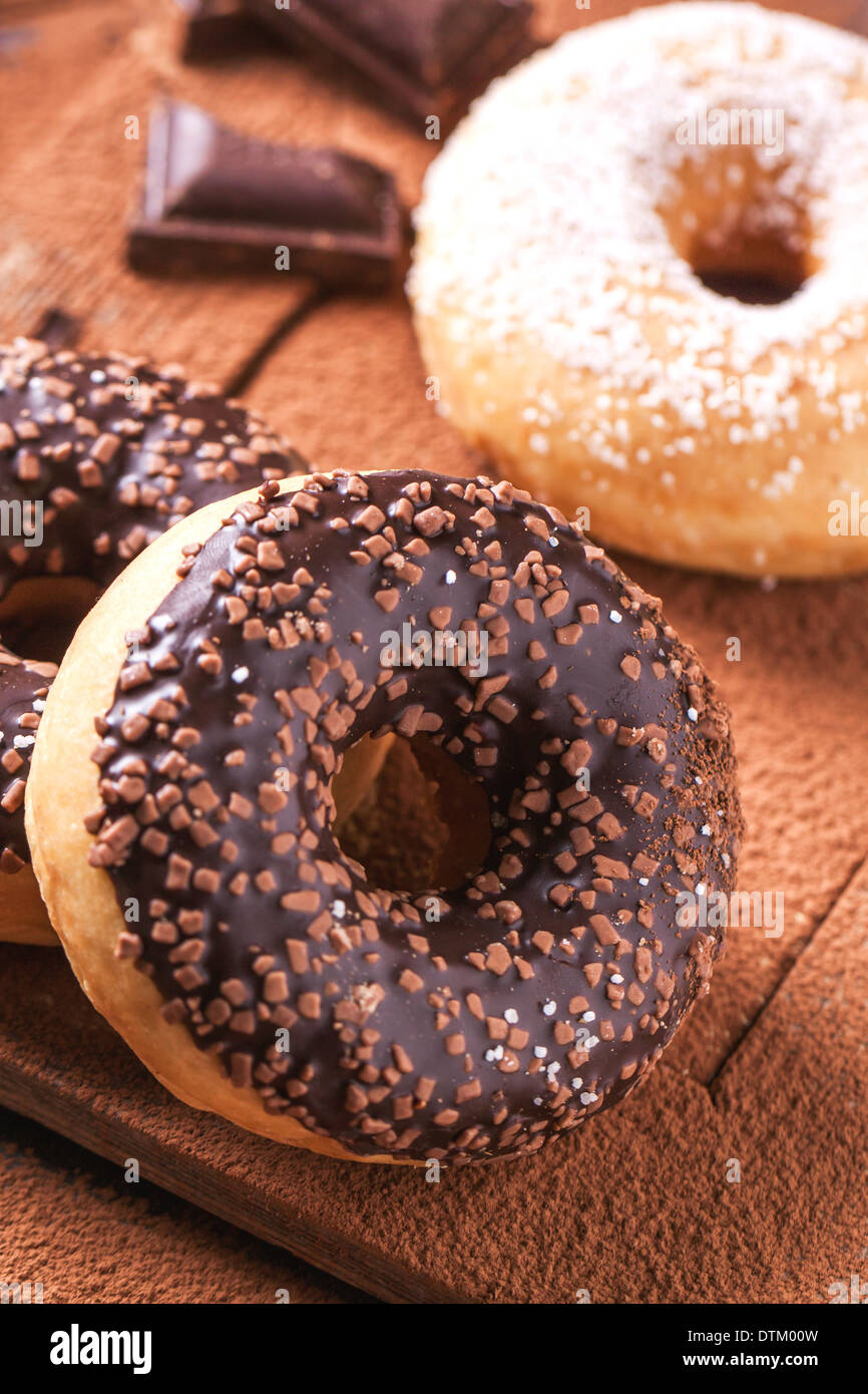 Chocolate donuts with dark chocolate served on cutting board with cocoa