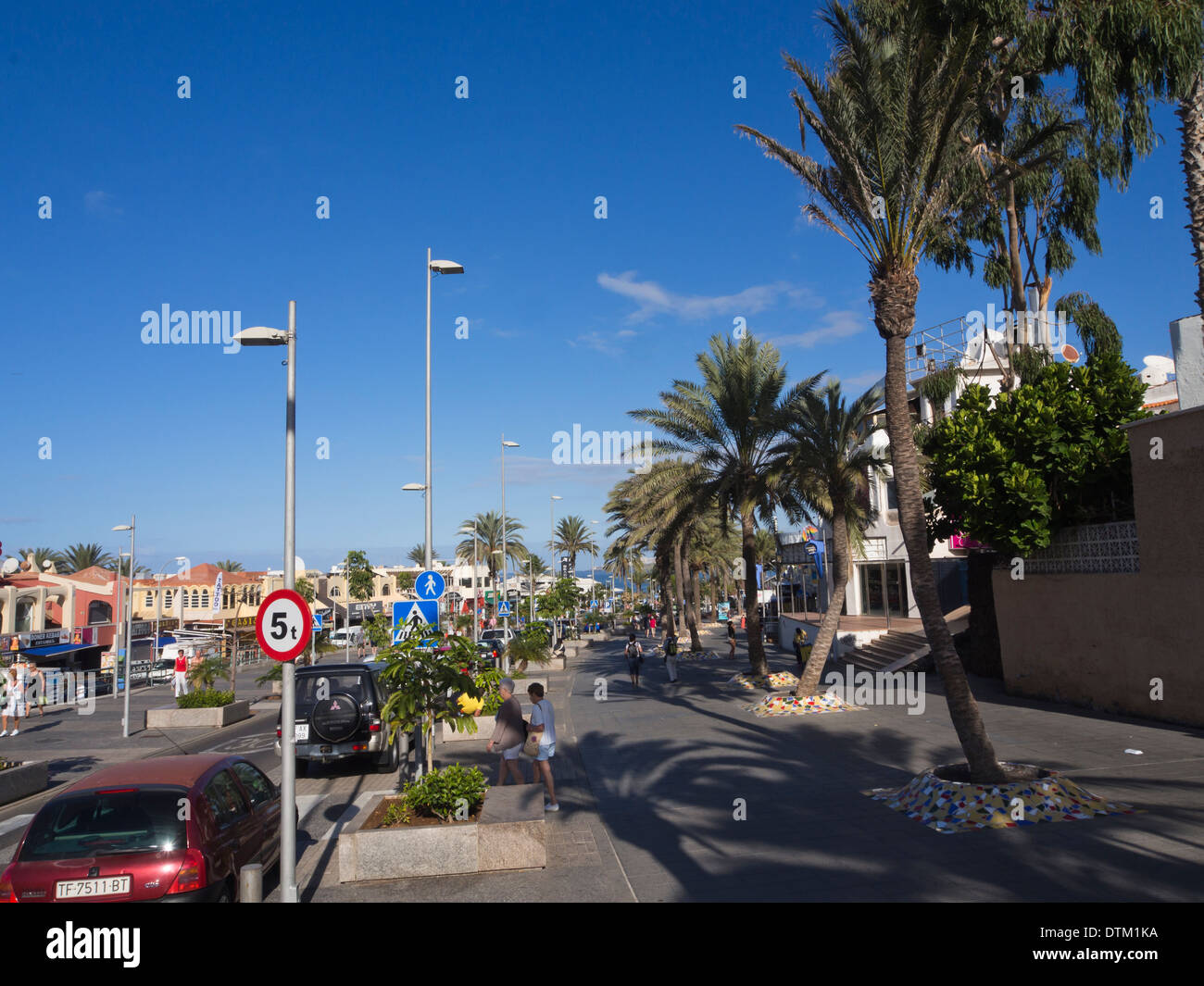 Palm lined street with wide pavements in the tourist resort of Playa de Las Americas Tenerife Canary Islands Spain Stock Photo