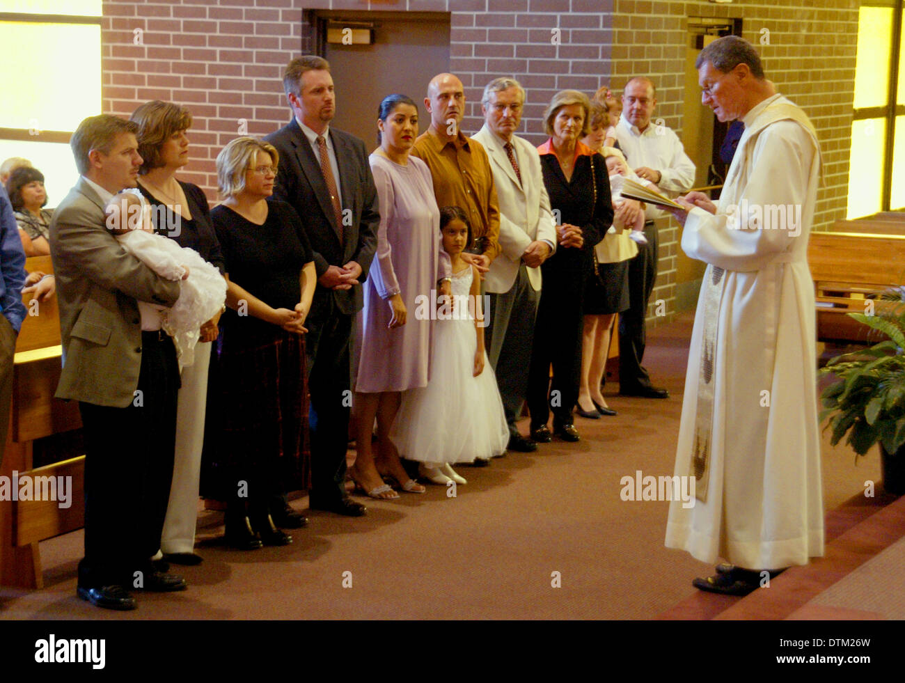 A robed Catholic priest reads a sermon to parents and children during