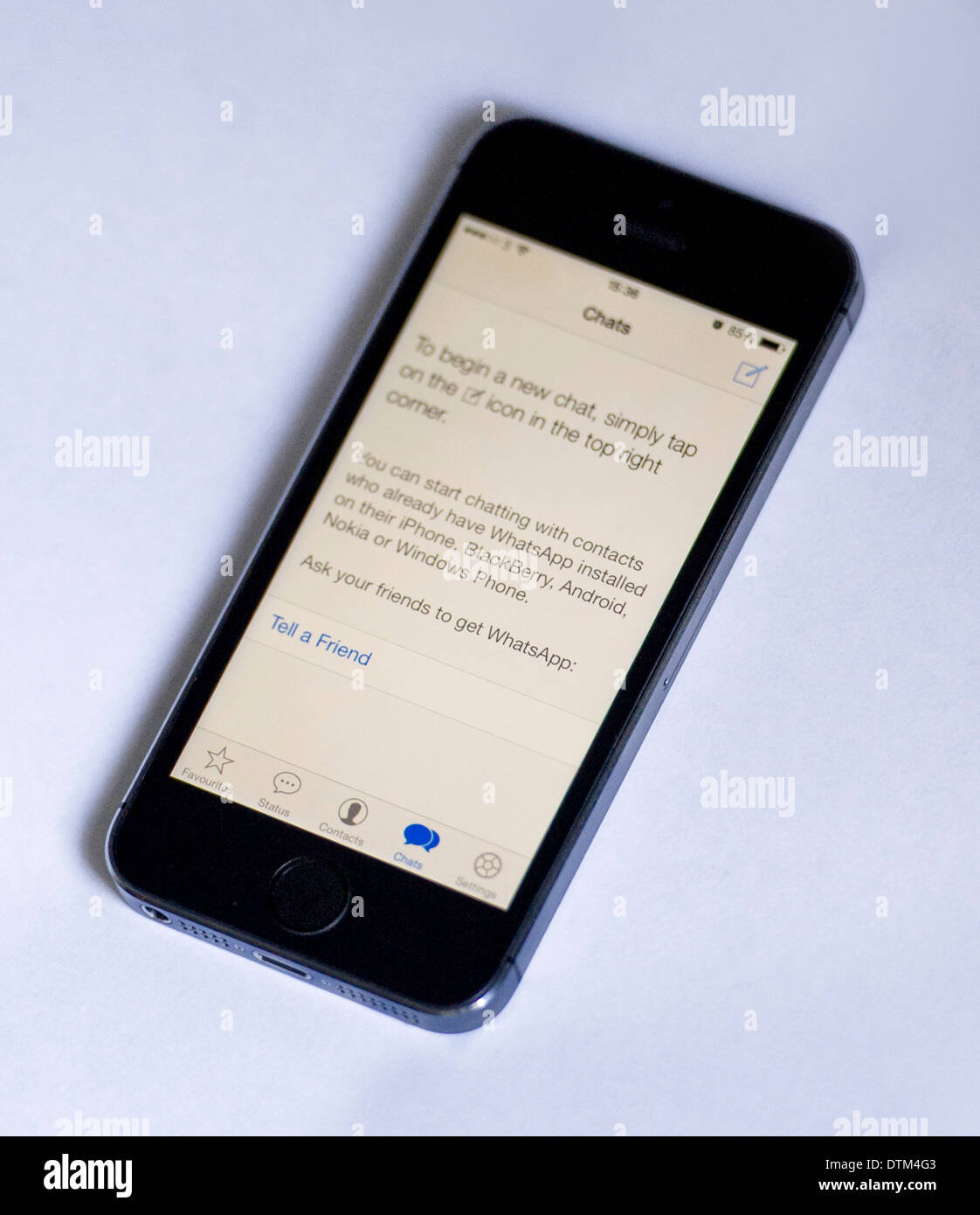 An iPhone 5S on a white  background, showing the Whatsapp app displaying instructions to start a new chat. Stock Photo