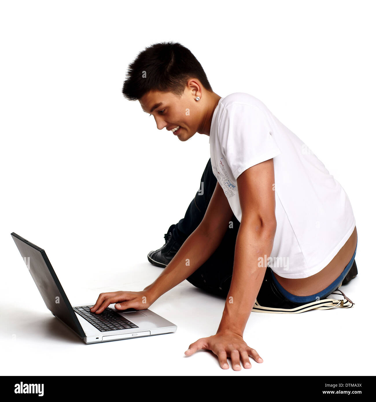 Pensive young man sitting on floor using laptop, isolated on white  Stock Photo