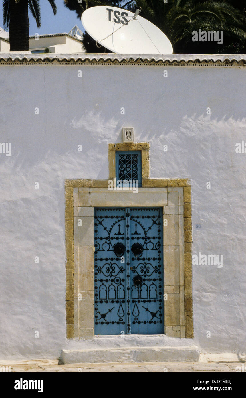 Tunisia, Sidi Bou Said. Decorated Door of a Traditional House.  Satellite Dish on Roof. Stock Photo