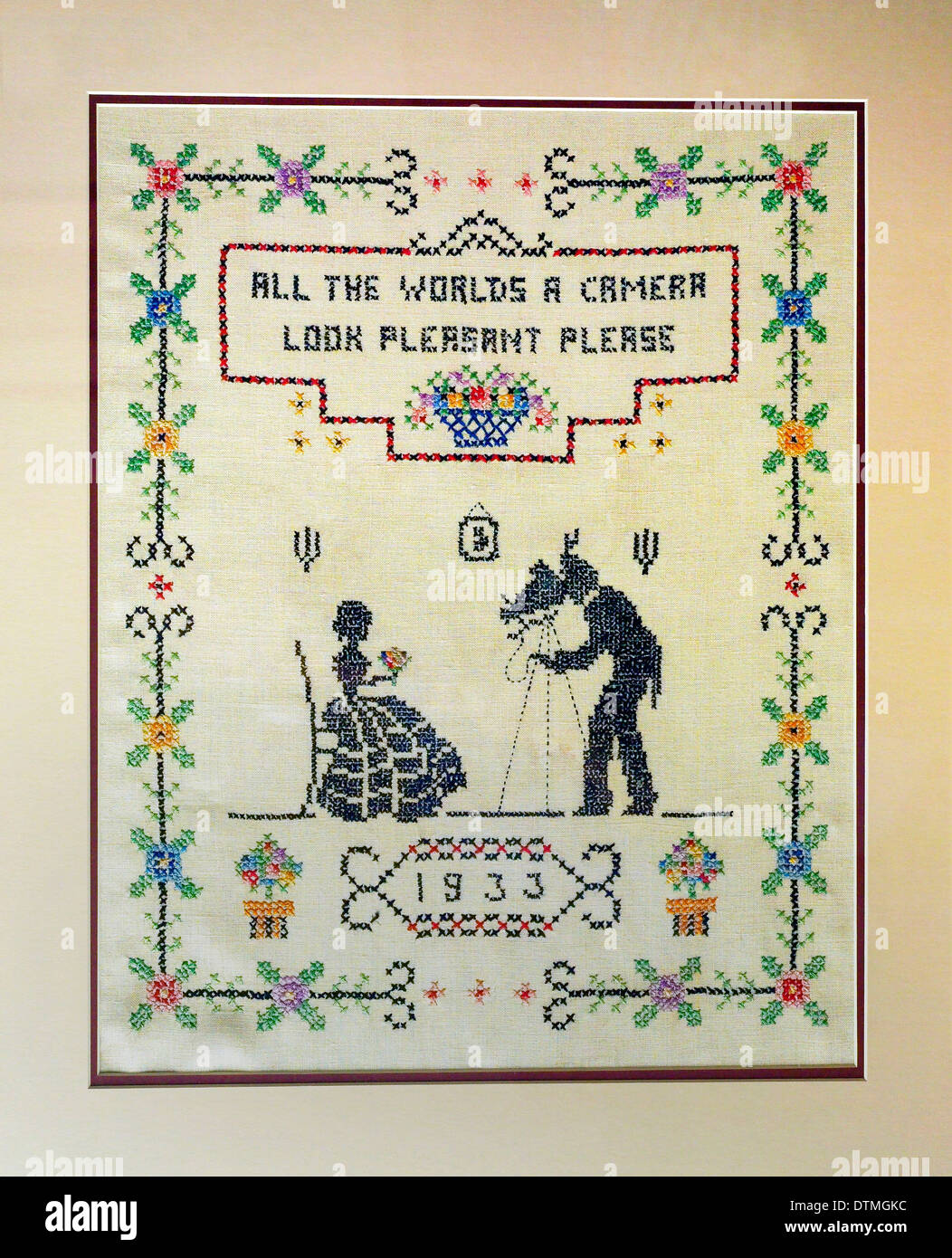 A clever verse highlights this 1933 needlepoint sampler that shows a photographer with an old-fashioned camera taking a formal portrait of a woman. Stock Photo