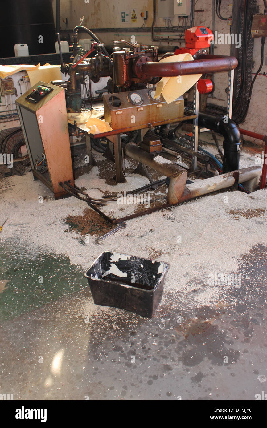 A Diesel fuel spill in a boilerhouse with absorbent pads and granules soaking up and containing the spillage Stock Photo