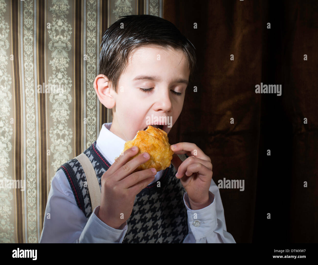 Child who eat donut. Vintage clothes and background Stock Photo