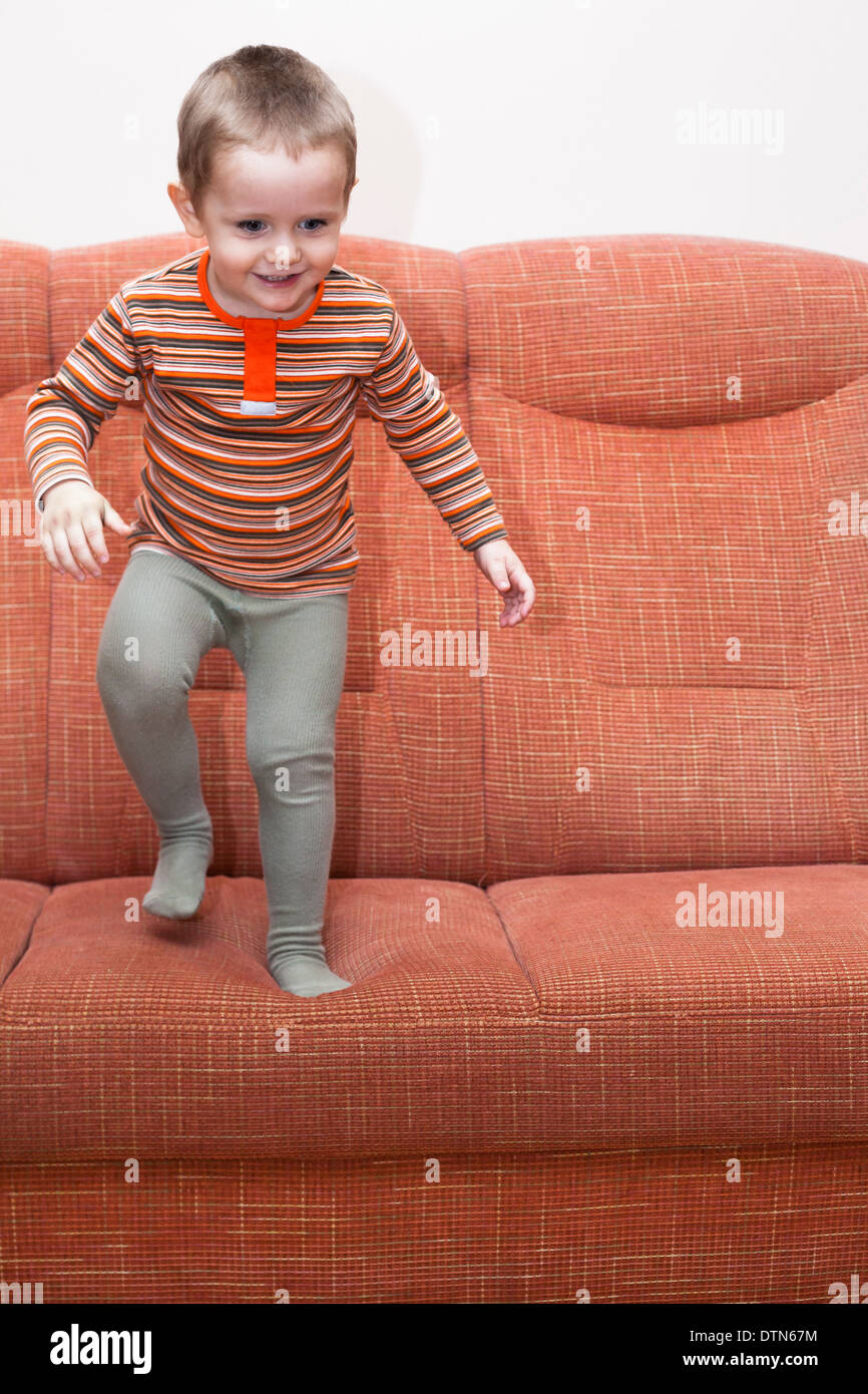 Happy playful child boy jumping on sofa. Stock Photo