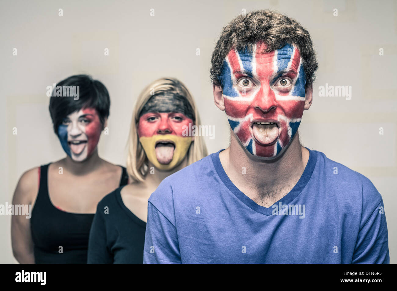 Group of funny people with painted European flags on their faces and sticking out tongue. Stock Photo