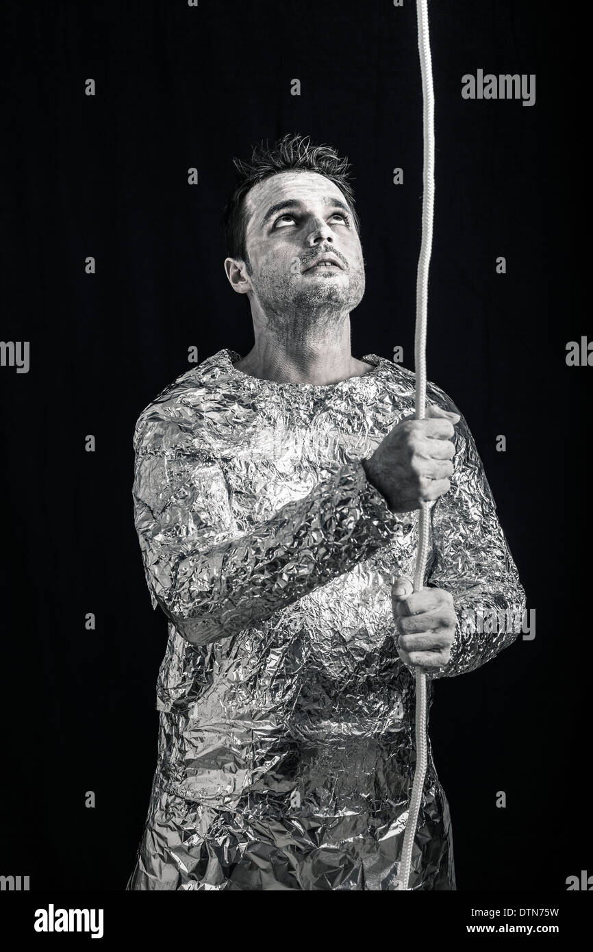 Curious spaceman holding rope and looking up. Stock Photo