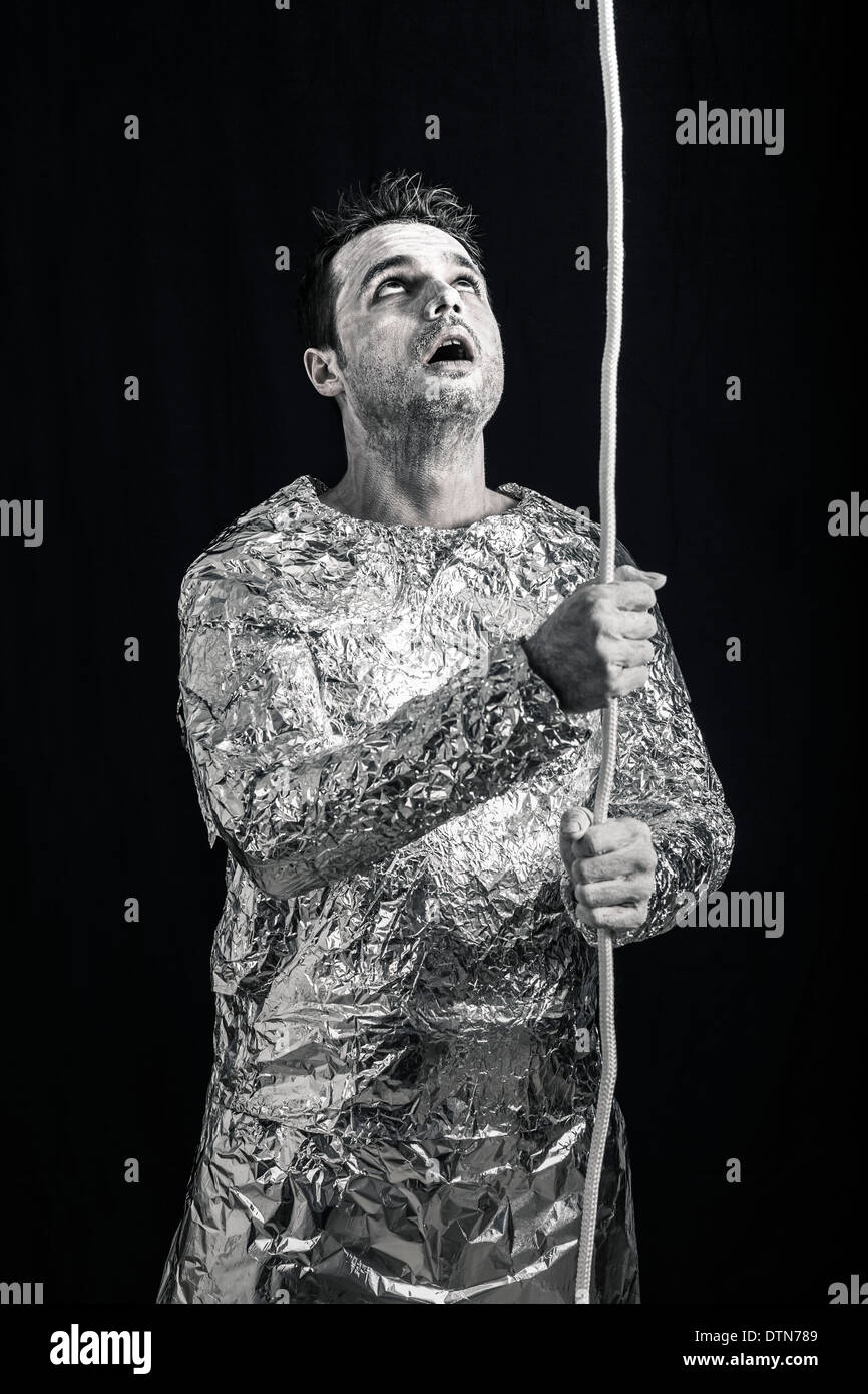 Surprised spaceman holding rope and looking up. Stock Photo