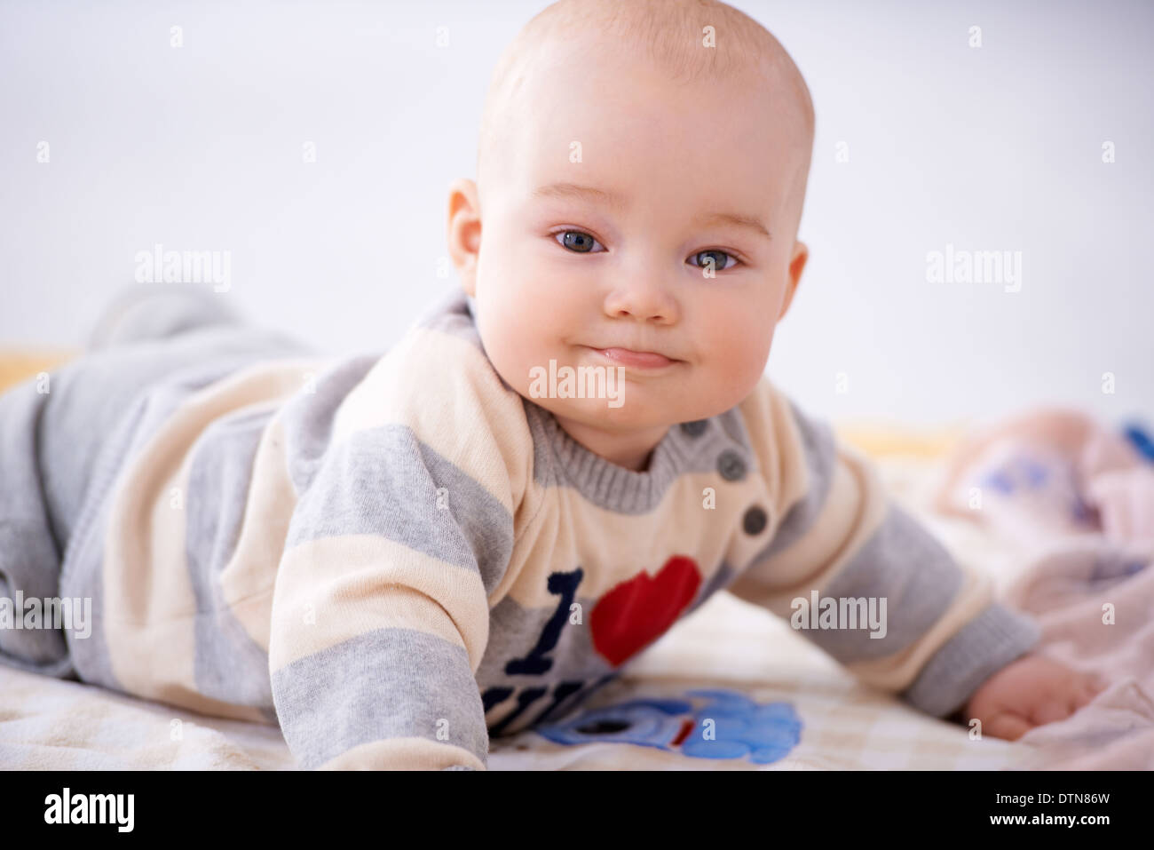 Contented little baby smiling at the camera Stock Photo