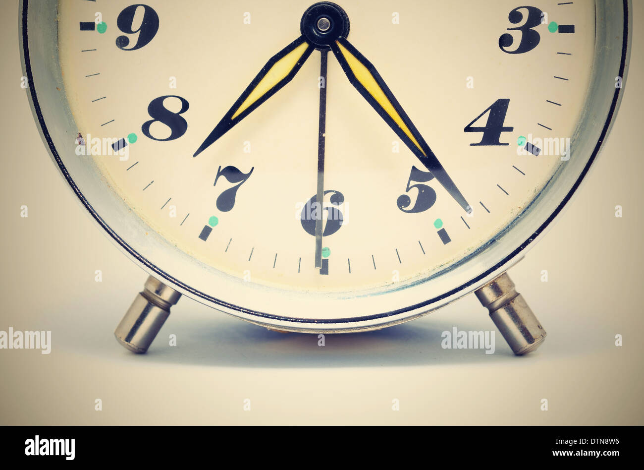 Closeup shot of the old dial alarm clock with yellow hands. Stock Photo