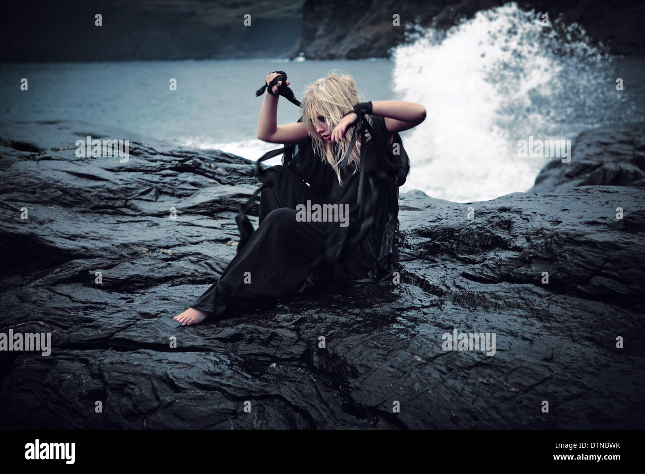 woman in black on rocks against crashing waves Stock Photo - Alamy