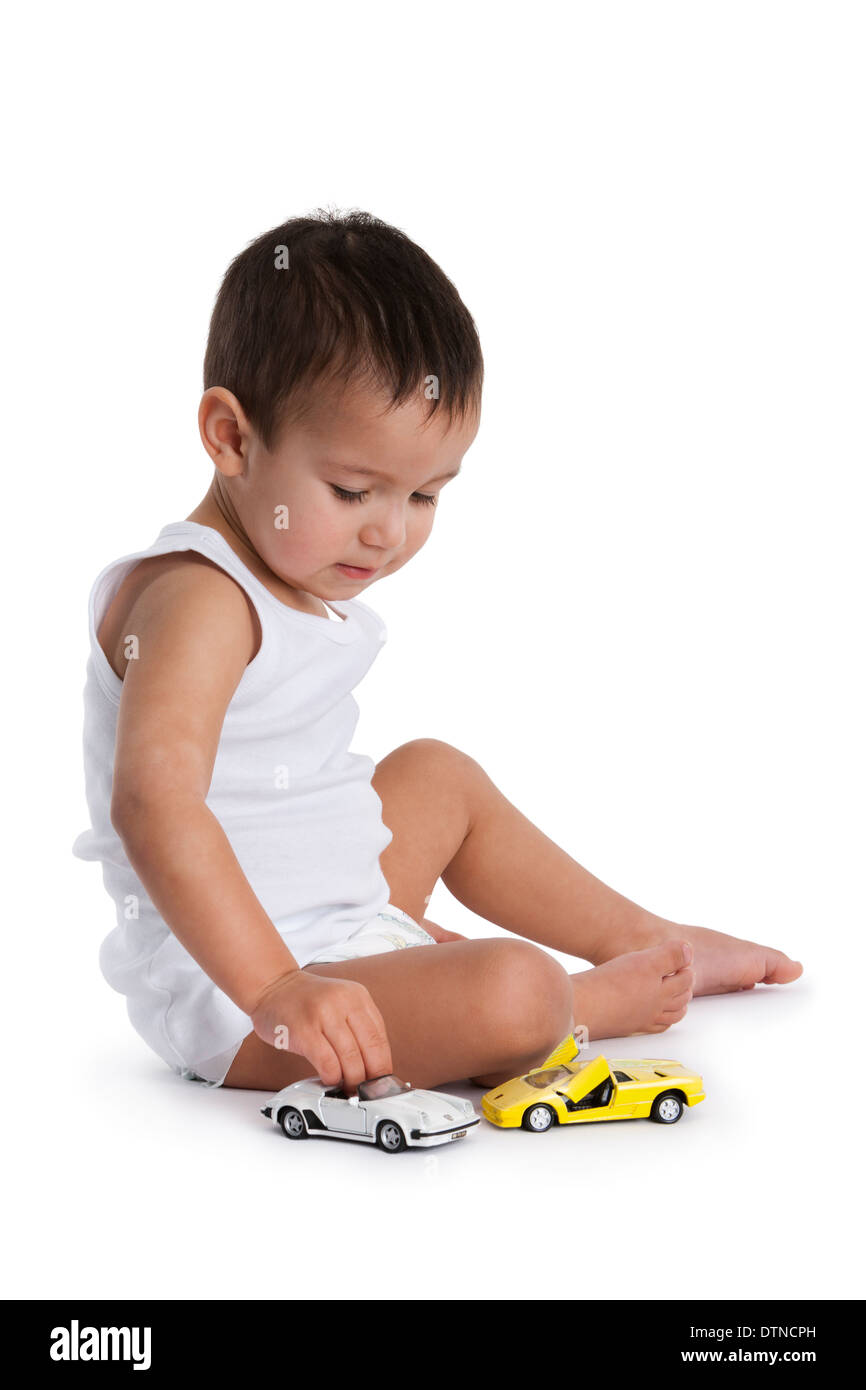 Toddler boy playing with toy cars on the floor on white background ...
