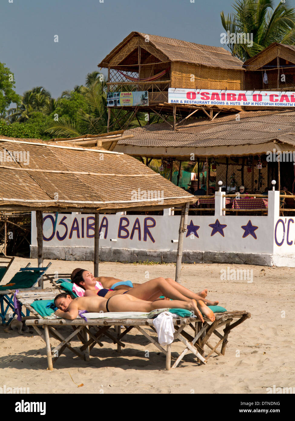 India, Goa, Mandrem beach, Russian women sunbathing on sunloungers at O’Saiba bar Stock Photo