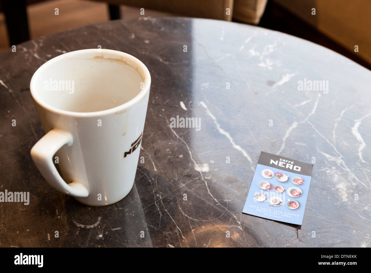 Full card. Caffe Nero loyalty card with all stamps filled in for a free cup, next to an empty mug of coffee Stock Photo