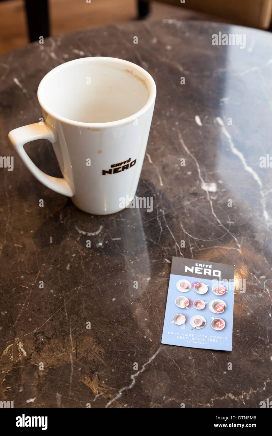 Fully completed Caffe Nero loyalty card with all stamps filled in next to empty cup of coffee Stock Photo
