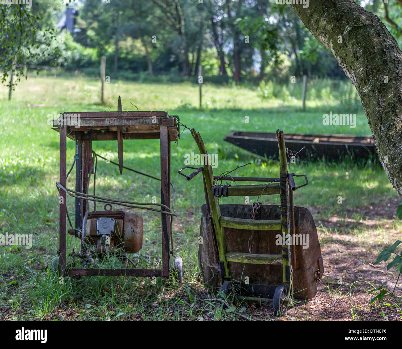 Rusty old farming equipment saw and wheelbarrow on a farm in the