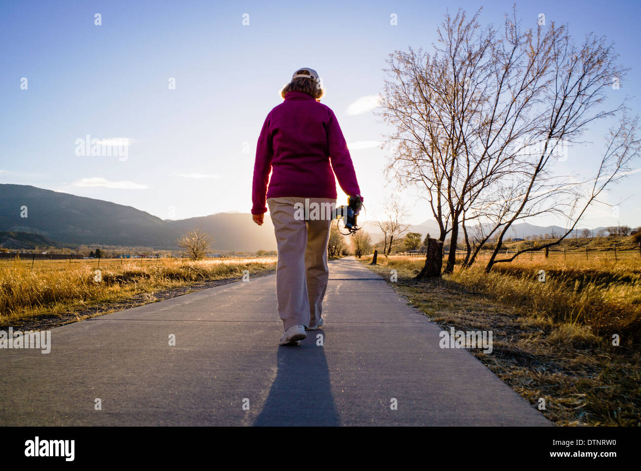 Woman walking on bike path at sunset, small mountain town of Salida, Colorado, USA Stock Photo