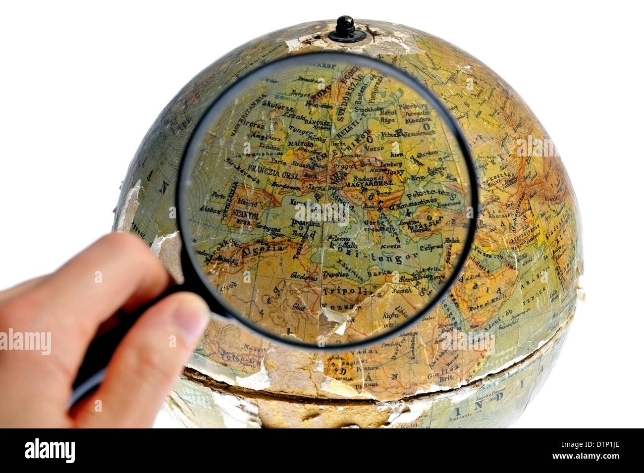 Hand holding a magnifier over an old rotating globe isolated on white background Stock Photo