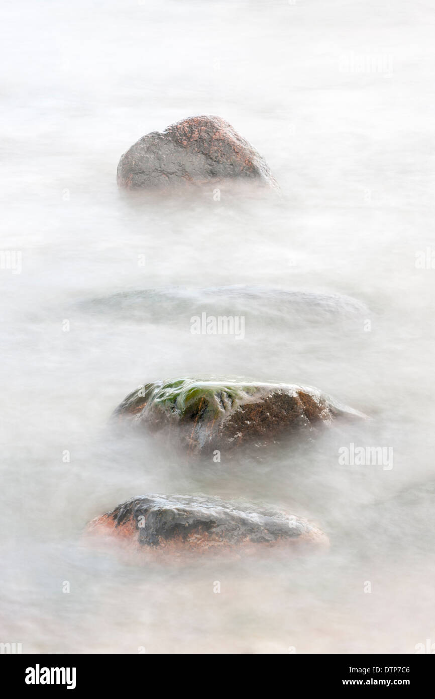 Four rocks in soft white water Stock Photo - Alamy