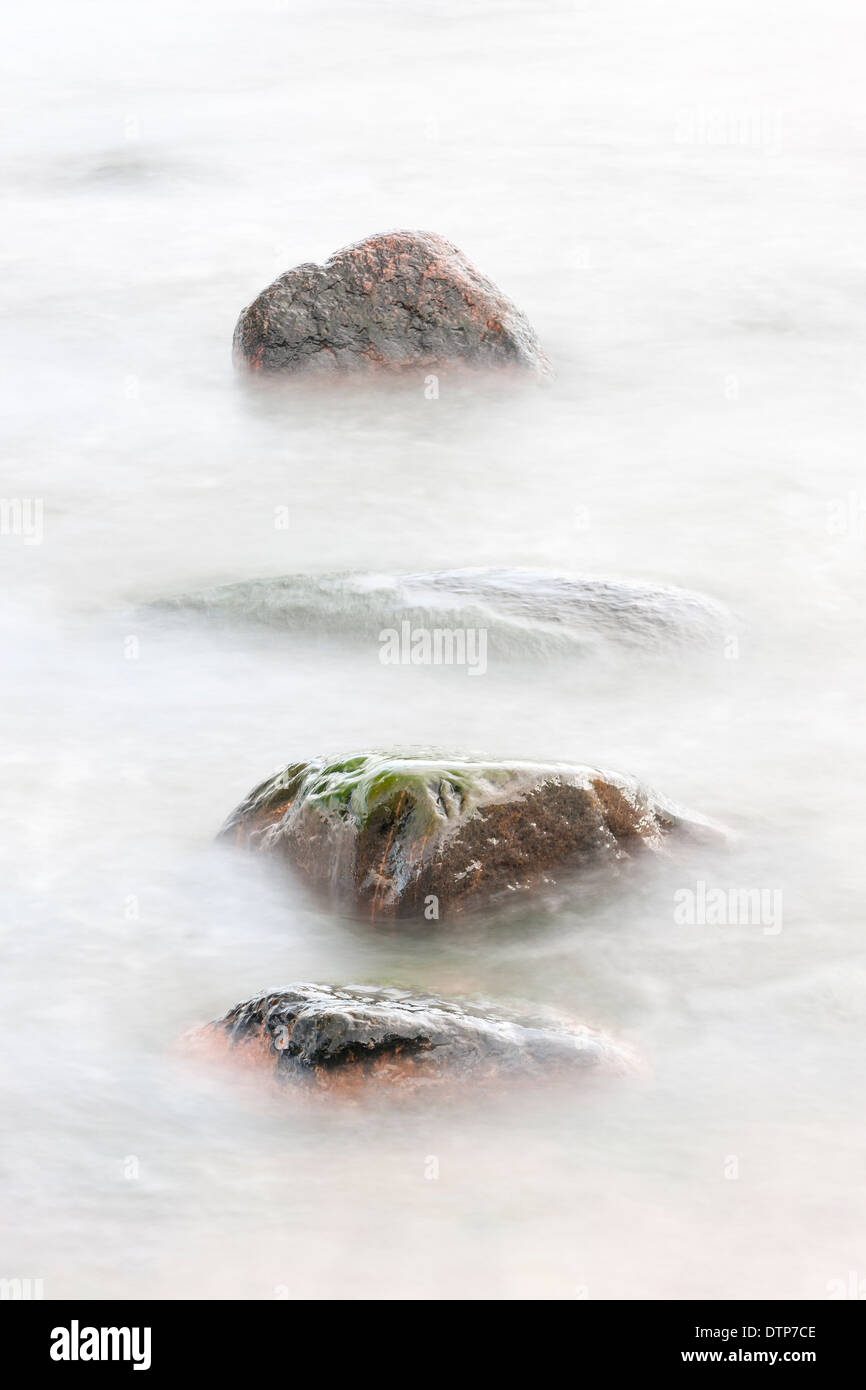 Four rocks in soft white water Stock Photo - Alamy