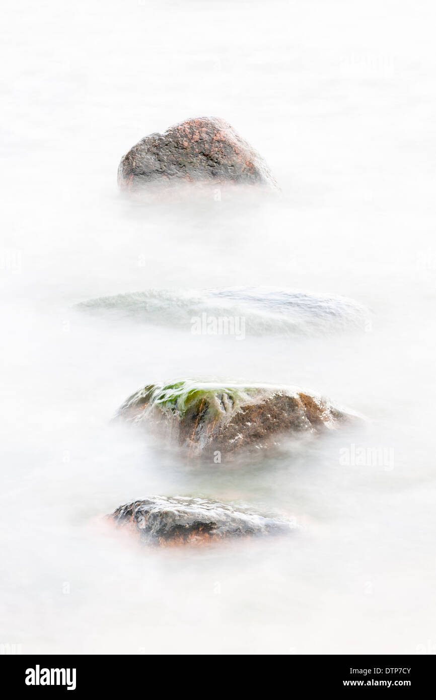 Four rocks in soft white water Stock Photo - Alamy