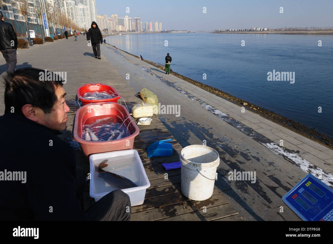 Fish seller on the Chinese side of the Yalu river. North Korea on the other side. Dandong, Liaoning province. China Stock Photo
