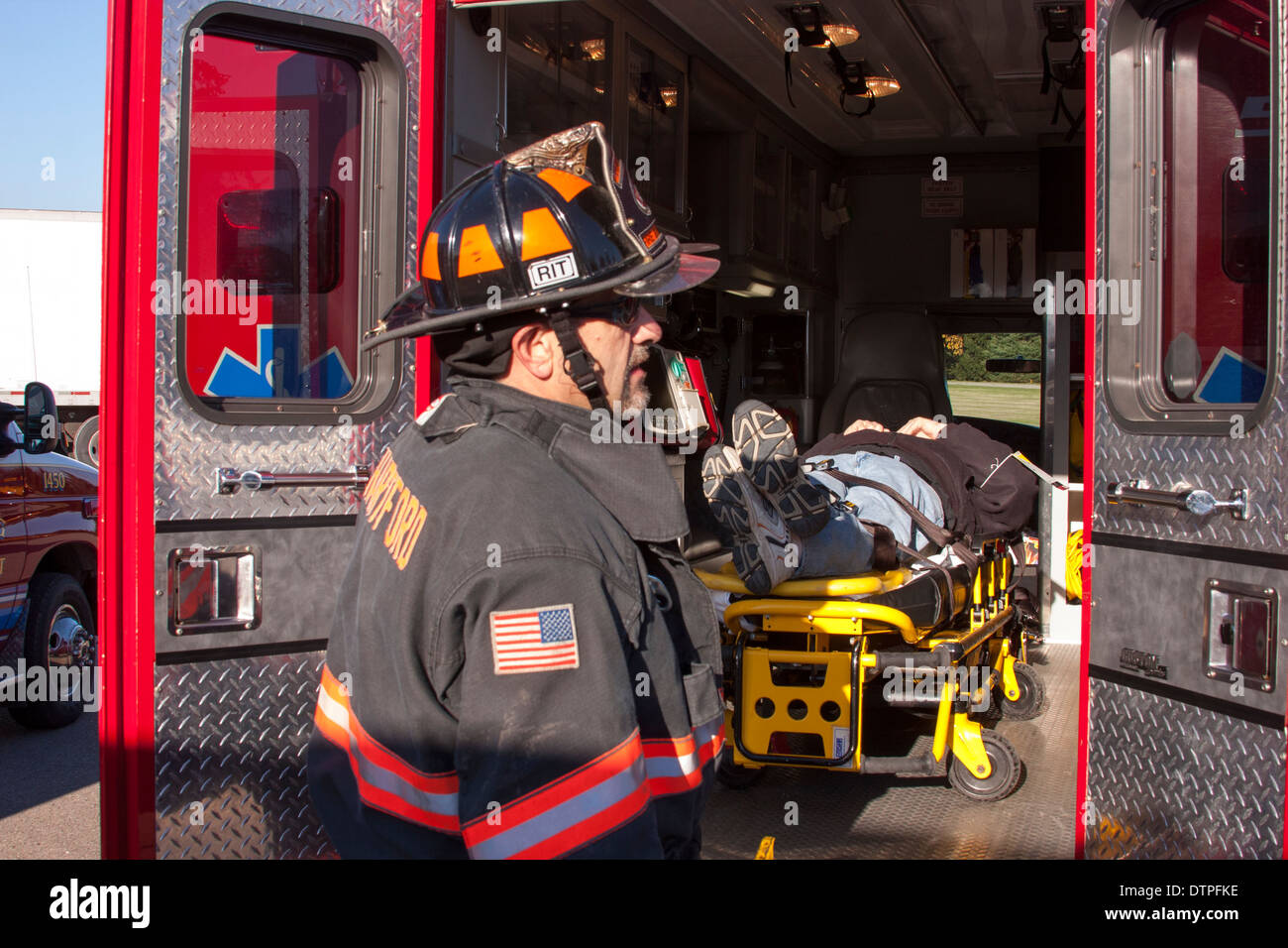 A Hartford WI firefighter putting a victim into an ambulance Stock