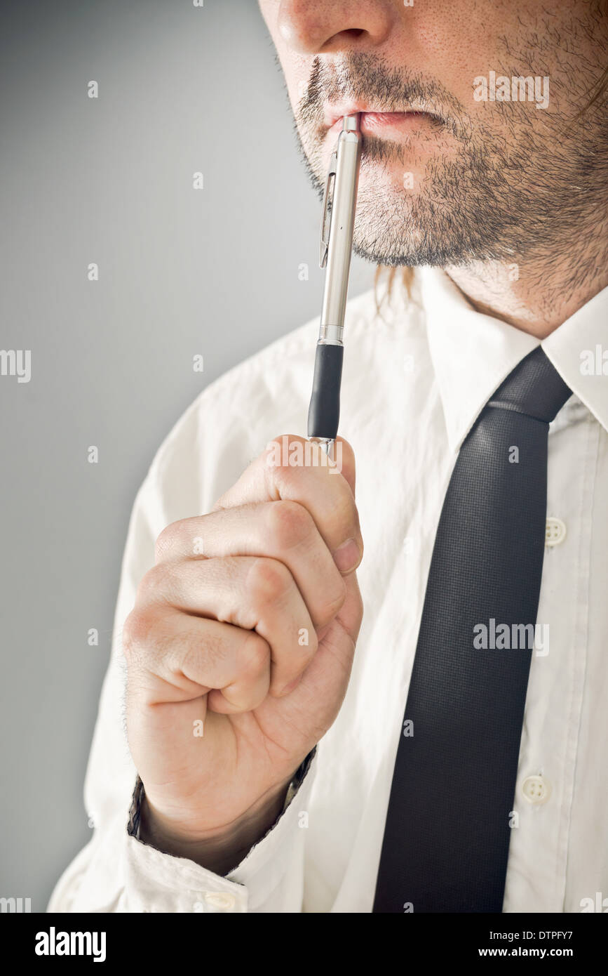 Businessman thinking with pencil in his mouth. Portrait of thoughtful business person. Stock Photo