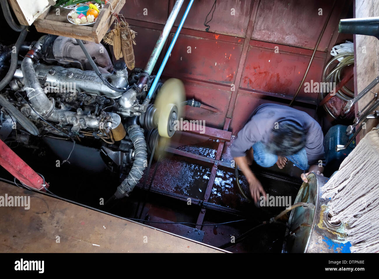 Crew member bailing water from the engine room of a 'slow boat' on the Mekong River in Laos. Stock Photo
