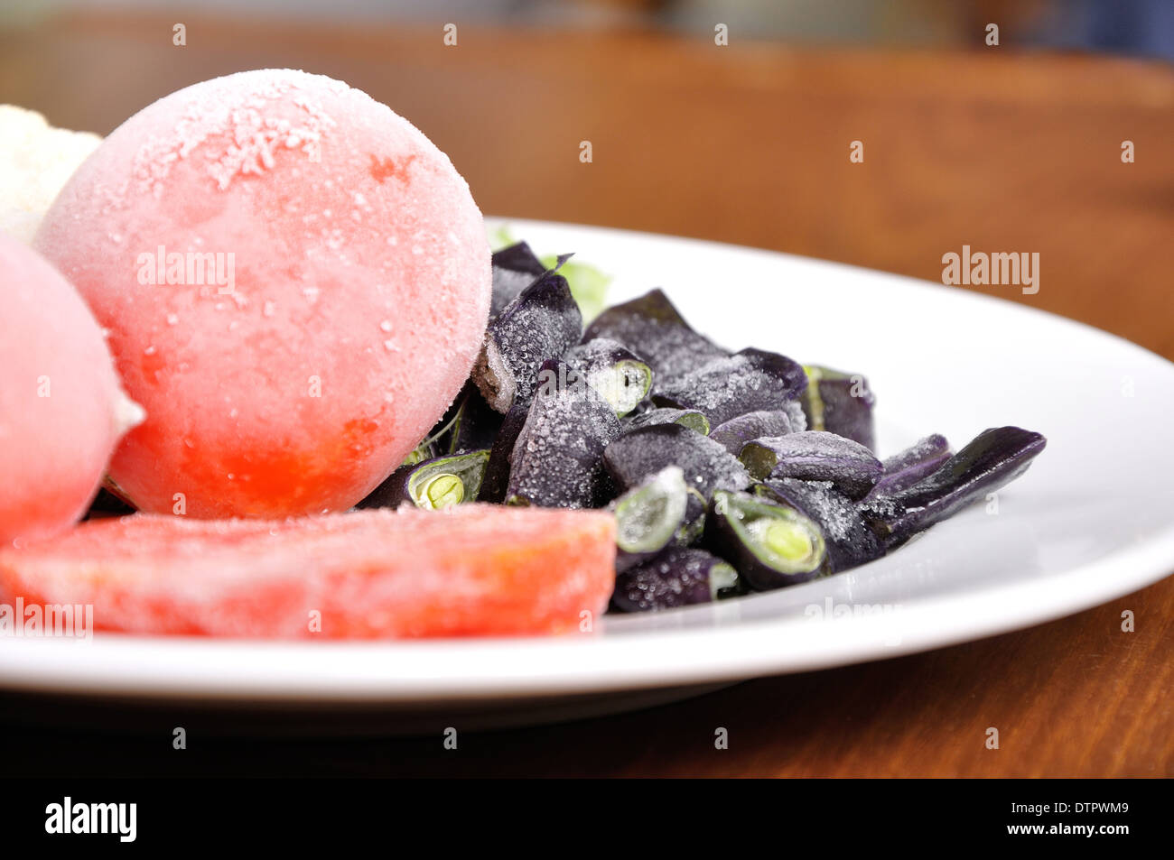 heap of frozen tomato and asparagus, on the white plate Stock Photo