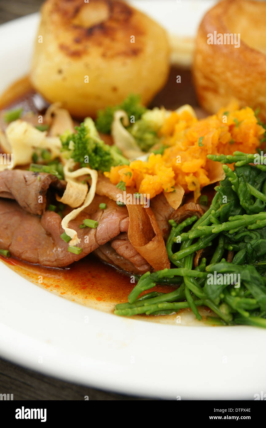 Roast beef dinner with roast potatoes, Yorkshire pudding and vegetables mashed swede and samphire Stock Photo