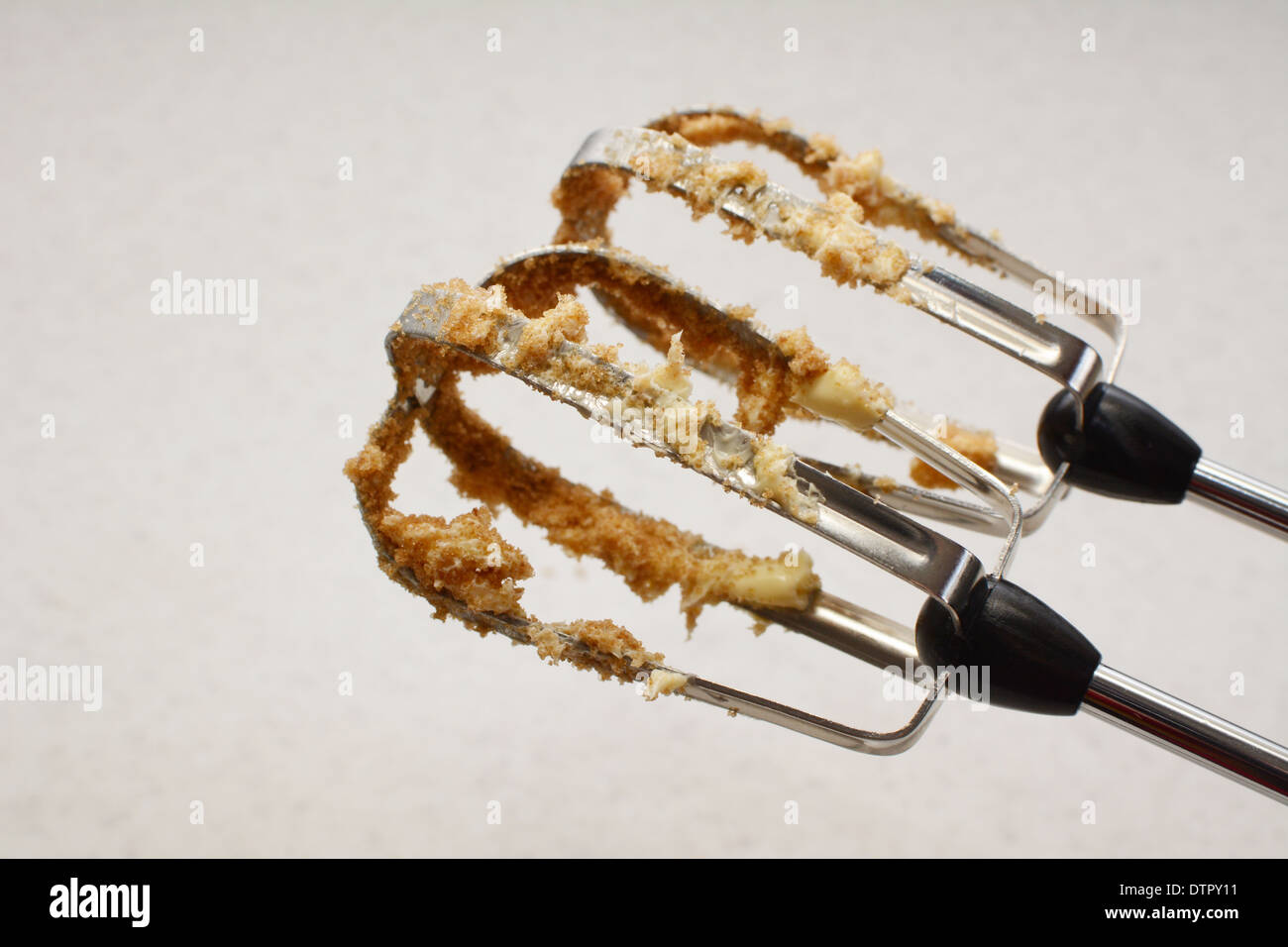 Closeup of electric whisk beaters covered in butter and muscovado sugar