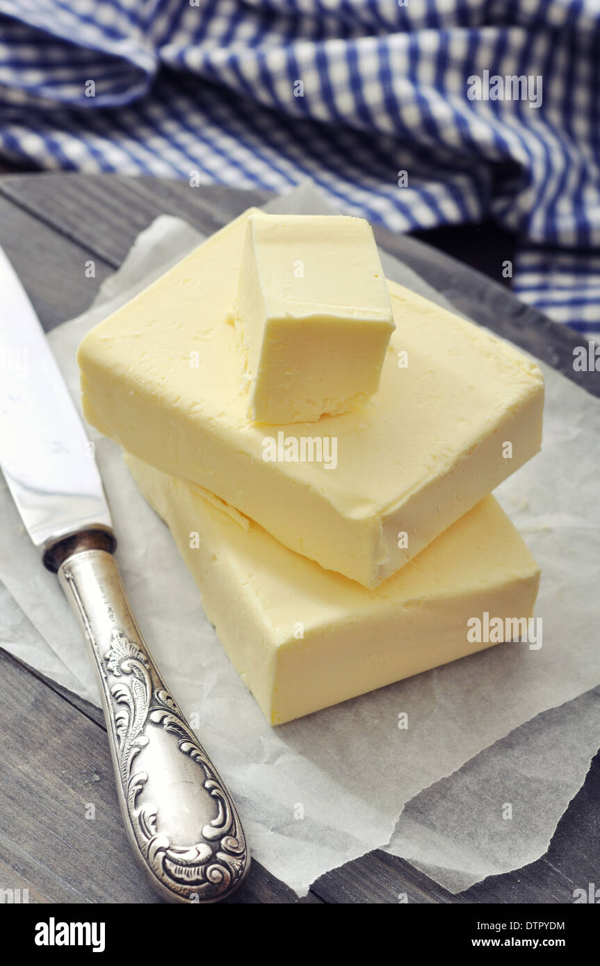 Fresh butter on wooden cutting board with knife closeup Stock Photo