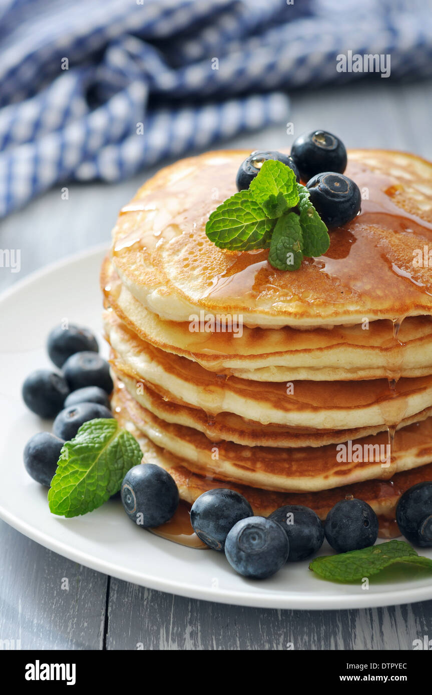 Pancakes with fresh berries, mint and maple syrup on white plate closeup Stock Photo