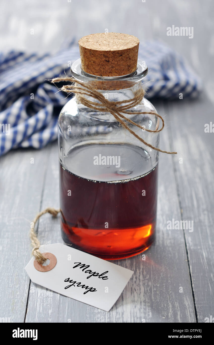 Maple syrup in glass bottle on a wooden background Stock Photo