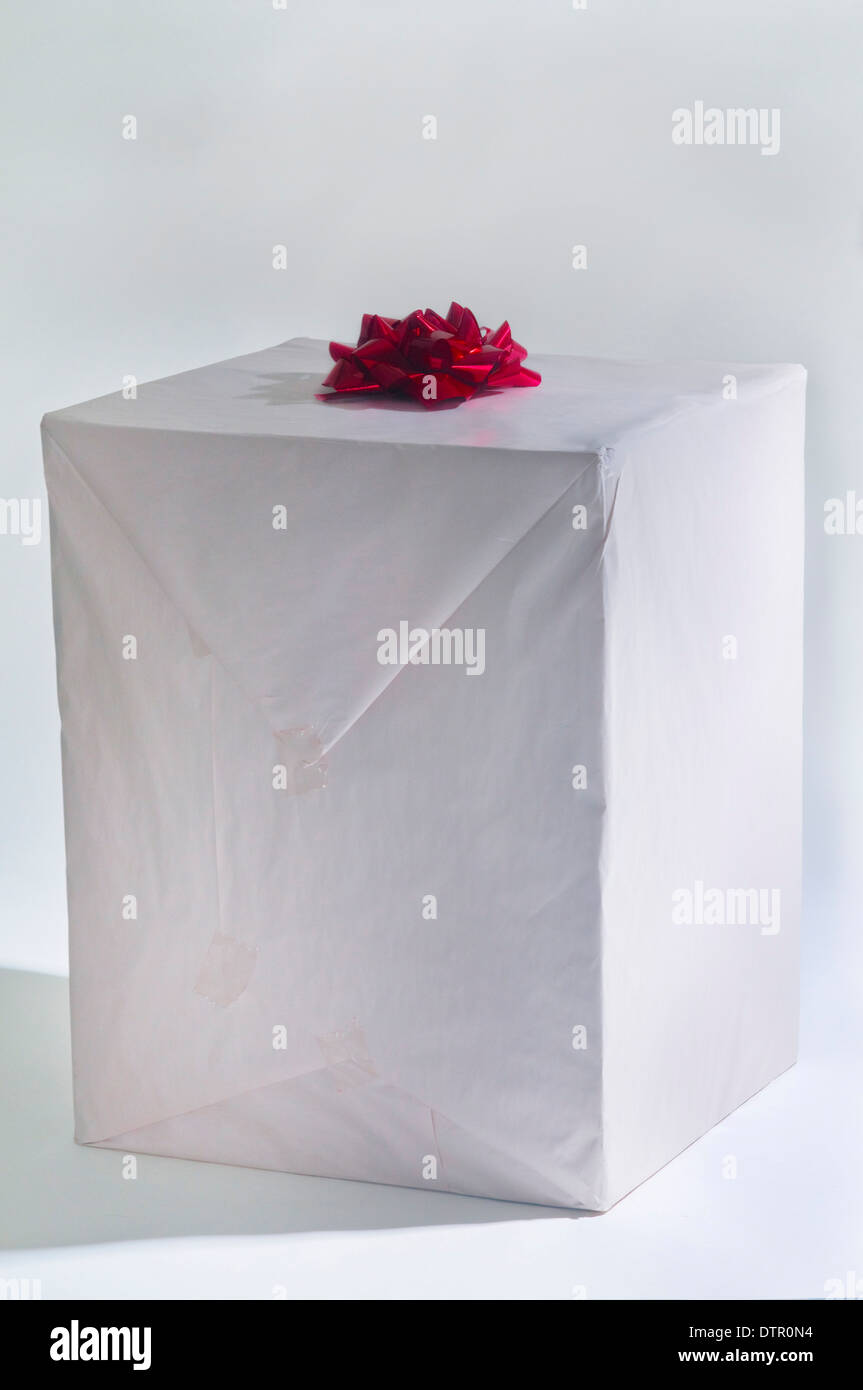 A Large Gift Box Wrapped In White Paper With A Red Ribbon On Top Stock 