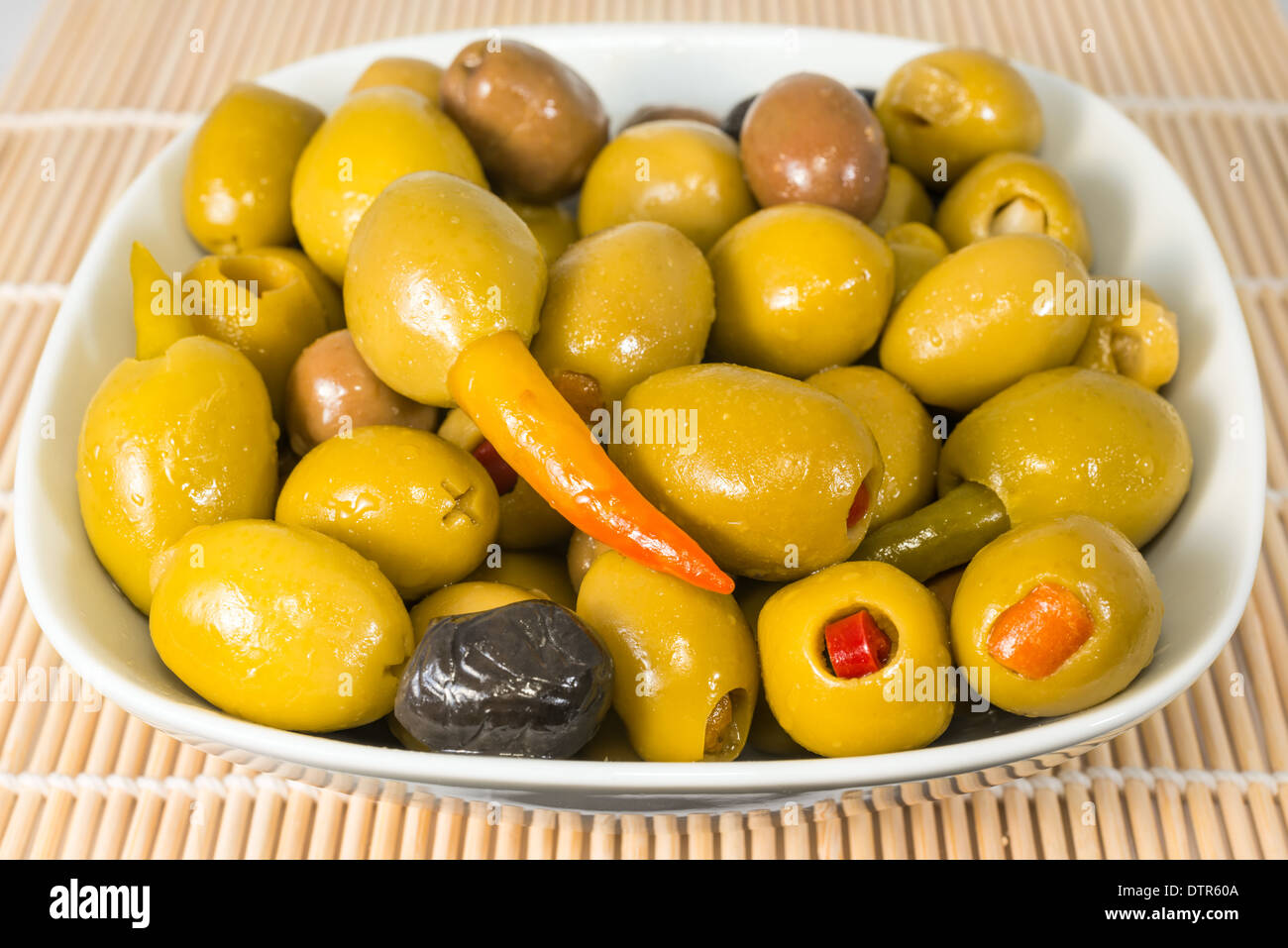 Green olives stuffed with pepper, orange and garlic in a plate lie on a