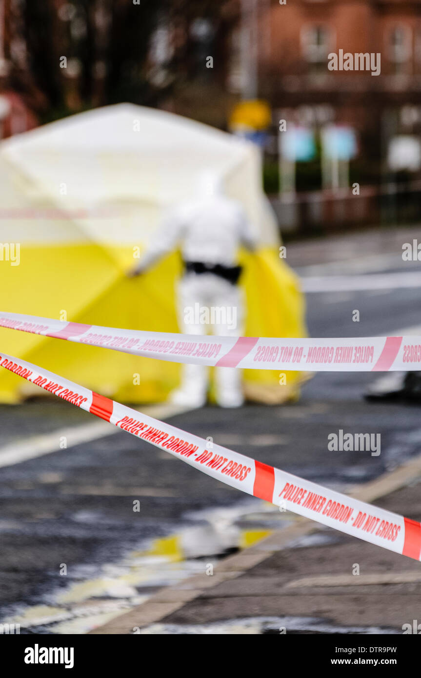 Belfast, Northern Ireland, 23rd February 2014 - Police tape forms a cordon outside a crime scene, with a forensics officer standing outside an examination tent Credit:  Stephen Barnes/Alamy Live News Stock Photo