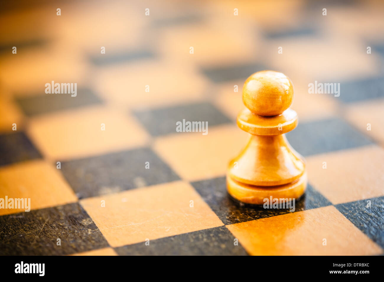 Chess white pawn standing on old vintage chessboard Stock Photo