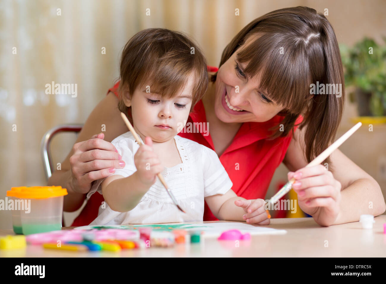 mother and kid girl paint together at home Stock Photo