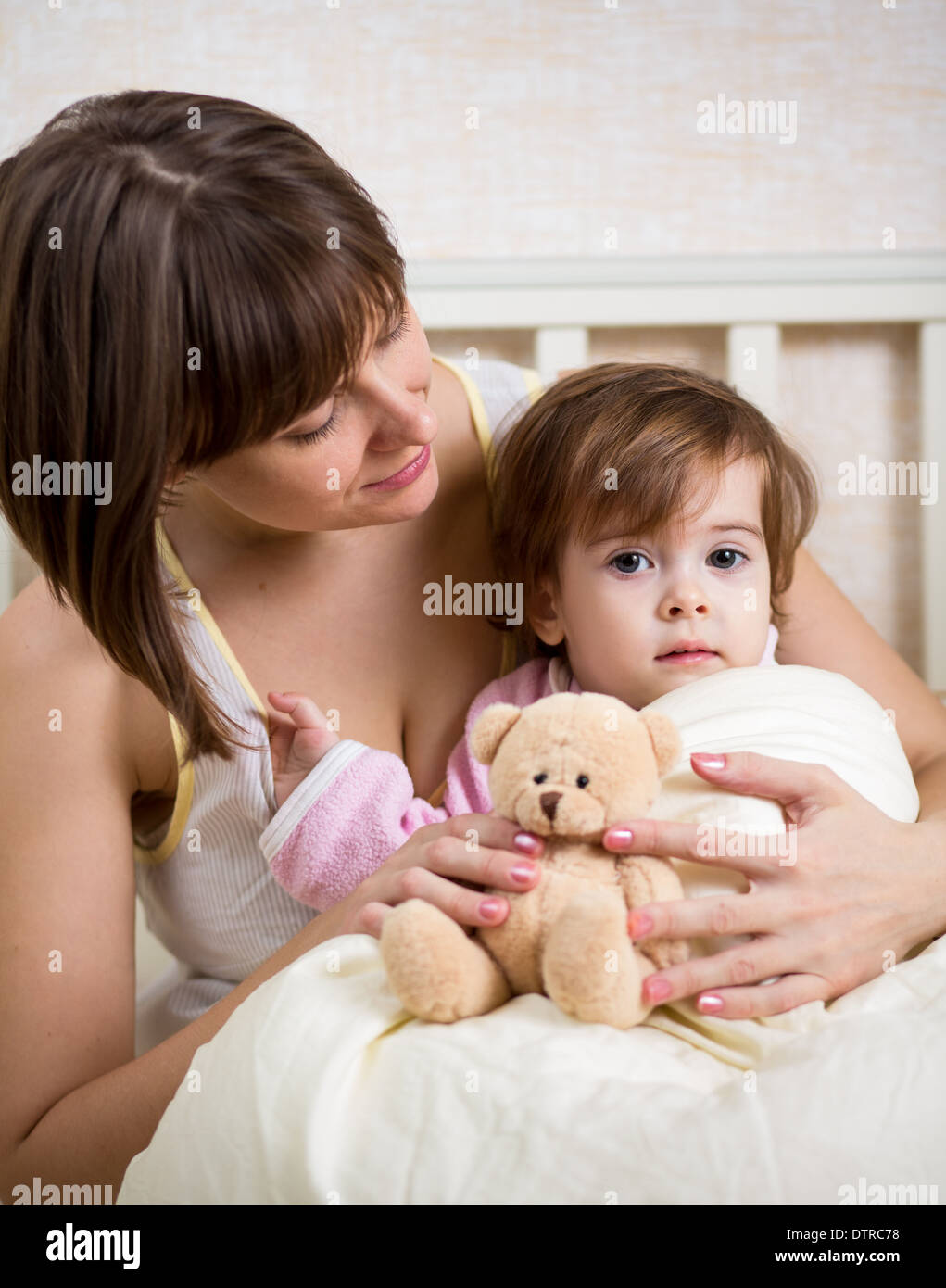 mother looking at kid in bed Stock Photo