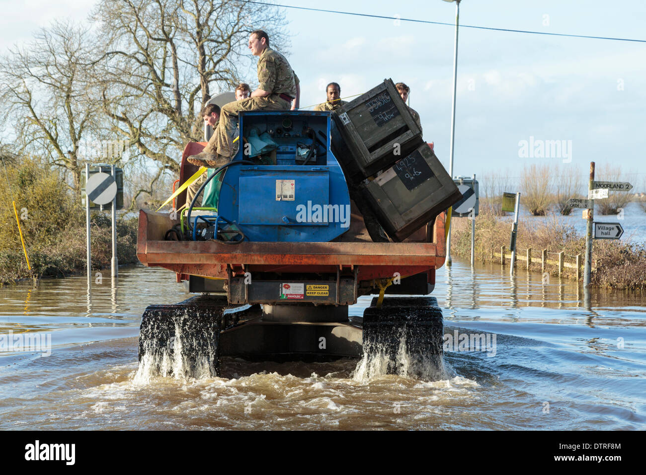 Burrowbridge, UK. 22nd Feb, 2014. Commandos helping at Burrowbridge on the flooded Somerset Levels on February 22, 2014. A group of soldiers are transported through the floodwater by workers of the Environment Agency in a Trac-dumper, a specialised vehicle capable of going through deep water. Supplies of oil and mechanical parts are sent to Saltmoor Pumping Station where water from Northmoor is being pumped into the tidal River Parrett to provide relief to the flooded area. These are the worst floods on the Somerset Levels in living history. Stock Photo