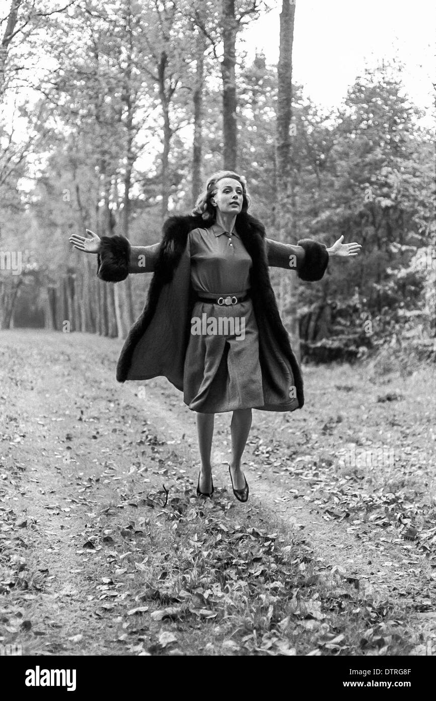 Sixties fashion model with fur coat running in forest Stock Photo