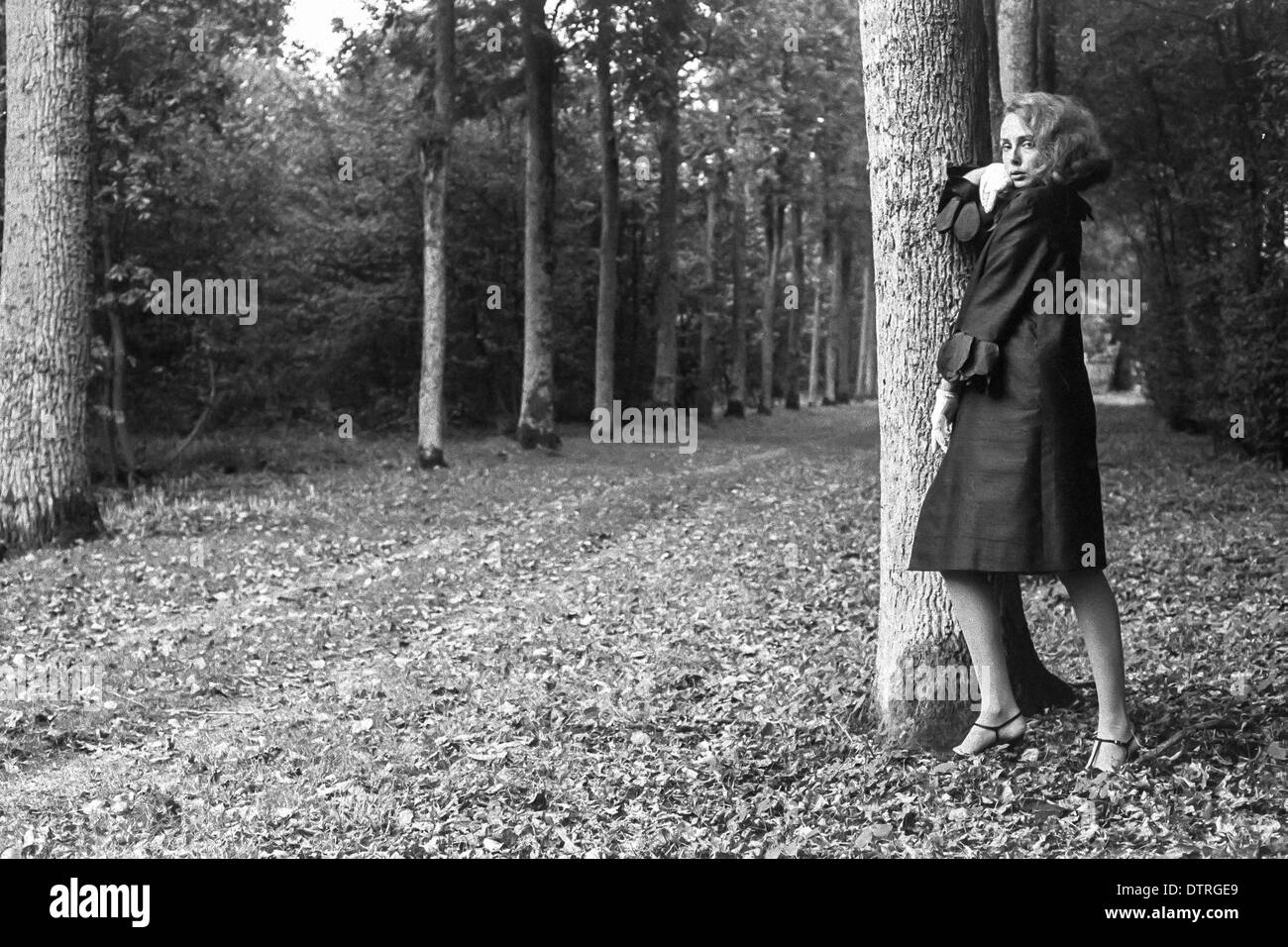 Sixties fashion model with black coat posing in forest Stock Photo