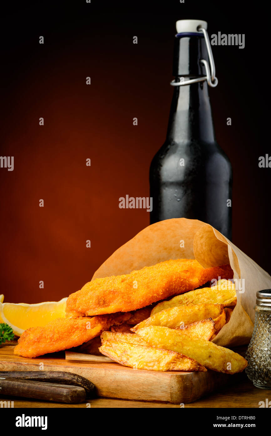 traditional fish and chips wrapped in paper and beer bottle Stock Photo